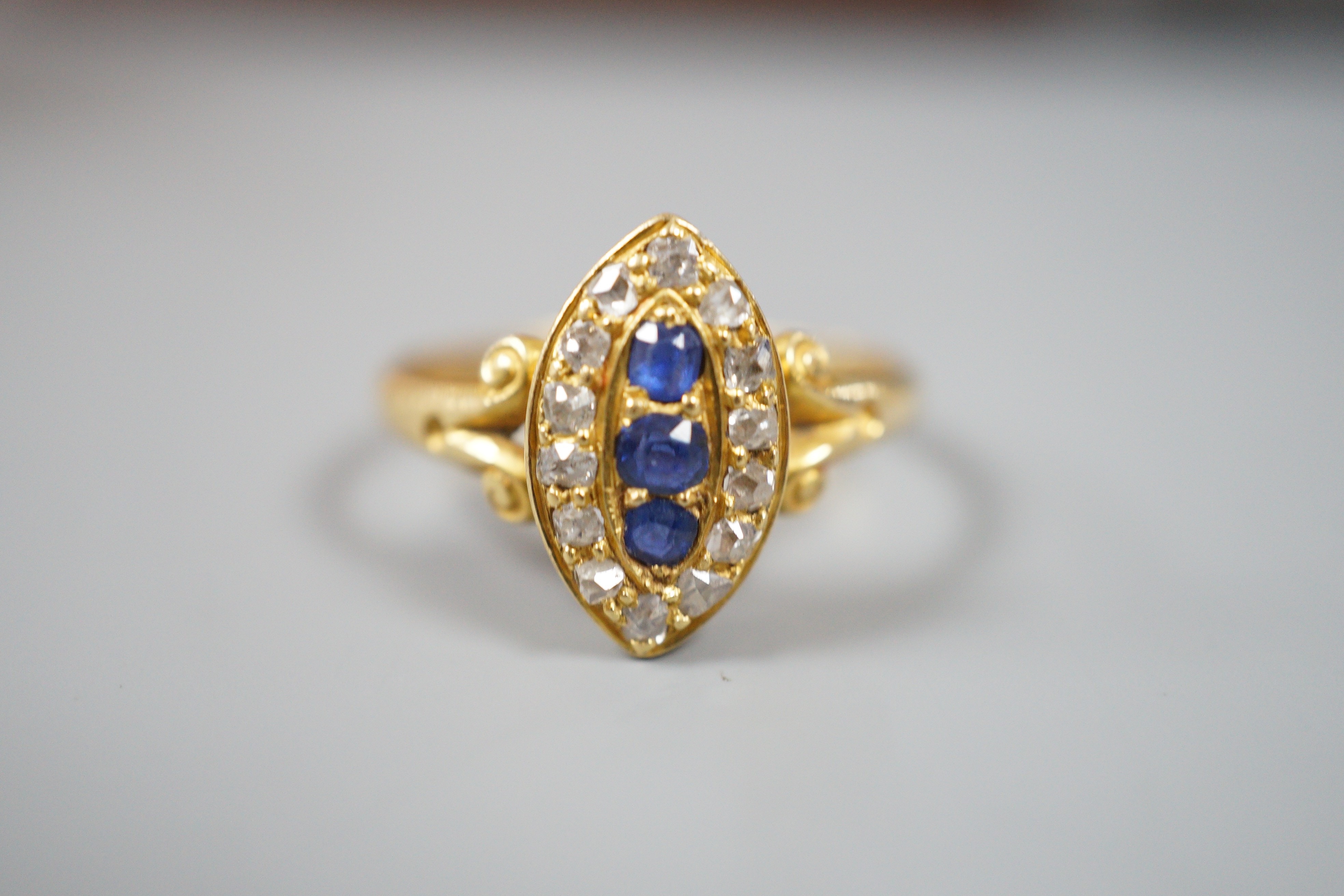 An early 20th century yellow metal, sapphire and diamond set marquise shaped cluster ring, with split shoulders, size R, gross weight 3.1 grams.